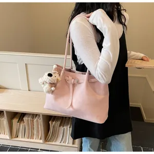 Vista detallada de bolso tote de hombro rosa con bonito colgante de peluche y correa lateral.