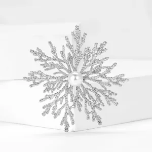 Close-up detail of silver snowflake branch brooch with central pearl accessory fashion.