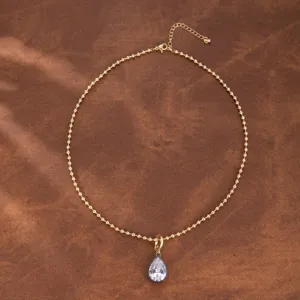 Vista detallada de collar con cadena de cuentas doradas y colgante de circonita brillante.