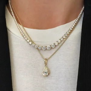 Primer plano detallado de collar de tenis de circonita en capas con elegante colgante de pera.