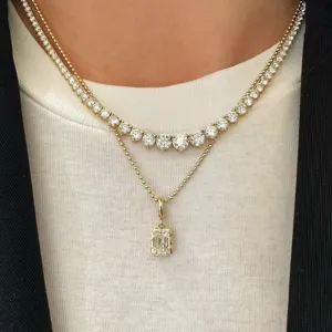 Primer plano detallado de collares dorados en capas con gargantilla de tenis y colgante.