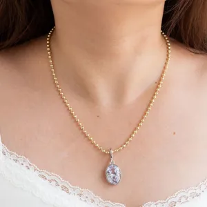 Primer plano detallado del elegante collar con colgante de circonita ovalada y cadena de cuentas.