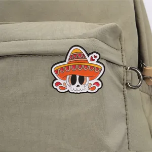 Close up view of the colorful Mexican sombrero skull metal brooch attached on green backpack detail.