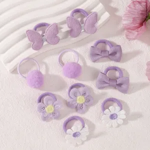 Close-up details of purple kids hair ties set, cute bows, pom poms and embroidered flowers.