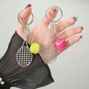 Metal tennis racket keychain with colorful mini plush ball pendant for backpack or keys.
