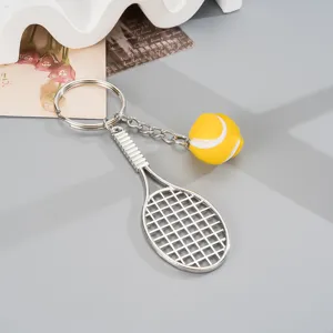 Metal tennis racket keychain with mini tennis ball charm, stylish backpack pendant.