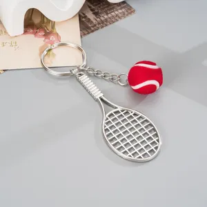 Fashionable metal tennis racket keychain with a mini red plush tennis ball charm for bags.