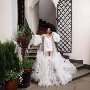 Detailed view of white tulle sheer robe with dramatic ruffled train and sleeves, elegant.