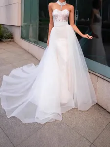 Elegant white wedding dress with sheer organza tulle train and lace bodice details.