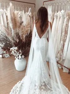 Stunning white lace backless wedding dress with long cape veil for bridal photography.