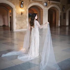 Elegant long wedding dress with flowing cape bridal gown for photography and ceremonies.