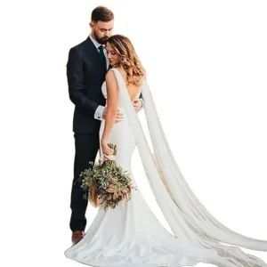 Elegant bridal wedding dress with long cape shawl and groom suit for photography.