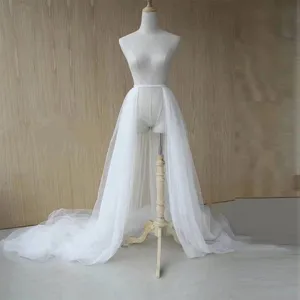 Detailed view of the white detachable tulle overskirt train, sheer mesh texture and high waist.