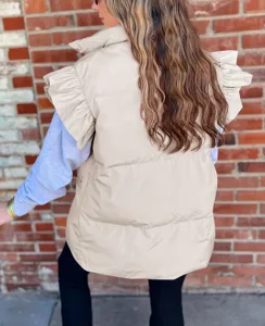 Detail shot of stylish women beige puffer vest featuring unique ruffle shoulders and stand collar.