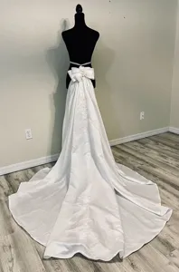 Detachable white satin wedding dress skirt with a large bow and long train for bridal photography.