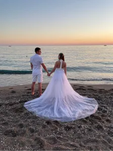 White tulle detachable skirt wedding dress with long train for beach photography detail view.
