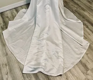 Detail view of the white satin wedding dress skirt with a long train and large hem.