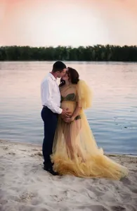 Detailed view of yellow tulle maternity dress with long train and puffy sleeves for photos.