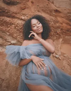 Outdoor maternity dress scene detail, elegant blue tulle fabric and off-shoulder design.