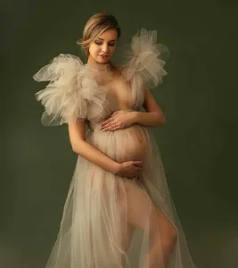 Detailed view of a sexy sheer tulle maternity dress with dramatic ruffled shoulders for photo shoot.