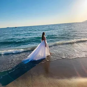 Elegant white detachable tulle wedding skirt with long train, perfect for beach bridal photography.