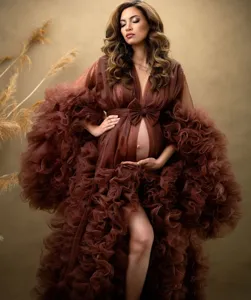 Stunning brown sheer maternity dress with dramatic ruffled sleeves and elegant bow detail for photos.