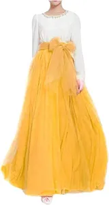 Detailed view of women's yellow tulle long skirt with large bow waist belt design.