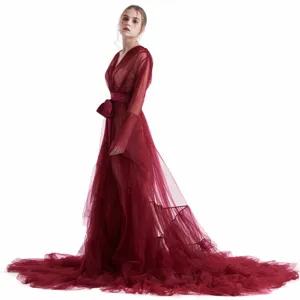 Dettaglio della lunga vestaglia in tulle bordeaux con cintura in satin e strascico.