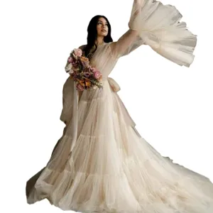 Elegant maternity tulle long dress with dramatic flared sleeves and delicate floral bouquet.