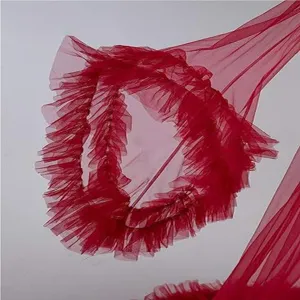 Detail view of red tulle ruffled fabric, elegant bridal gown trim and romantic robe.