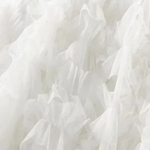 Close-up detail of white mesh tiered cake skirt fabric, showing soft layered ruffles.
