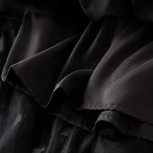 Black mesh tiered skirt detail close-up showing layered fabric texture and fine craftsmanship.