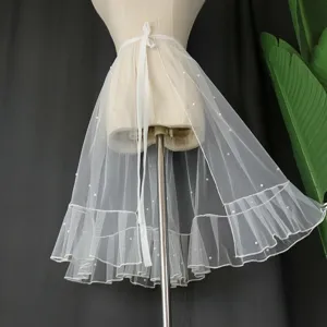 Detailed view of white sheer mesh wrap skirt with pearls and ruffles, ideal for summer layering.