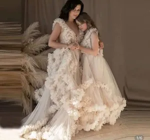 Detail shot of champagne tulle maternity dress and matching child gown with floral appliques.