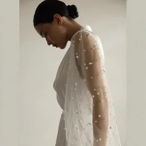 Detailed view of white pearl mesh bridal robe sleeve, elegant French style wedding dress fabric.