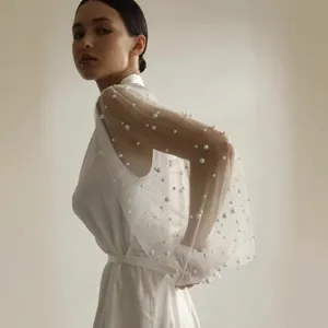 Elegant white slip dress featuring sheer pearl-embellished mesh long sleeves for bridal wear.