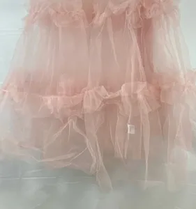 Close-up detail of the pink layered tulle skirt, showing soft ruffles and delicate mesh fabric.