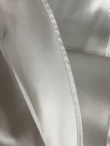 Primo piano del bordo strascico sposa in raso bianco, cuciture fini e tessuto liscio e morbido.