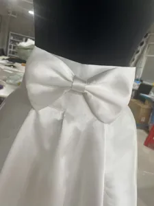 Dettaglio fiocco in raso bianco per accessorio abito da sposa, vita in primo piano.