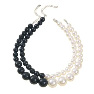 Collar statement de cuentas superpuestas en blanco y negro con cadena de extensión.
