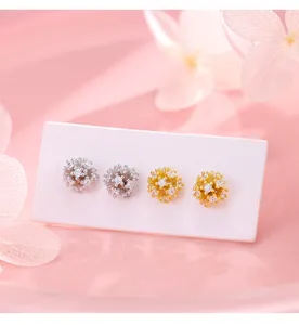 Primer plano de pendientes de tuerca de diente de león de circonita brillante plata oro, detalle.
