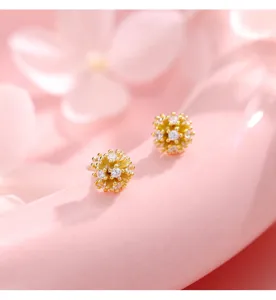 Detalle de pendientes de plata con circonitas en forma de fuego artificial fondo rosa suave.