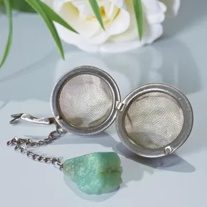 Stainless steel tea infuser featuring a mesh ball and raw crystal pendant chain for brewing.