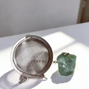 Close up of stainless steel mesh tea infuser detail with natural green crystal stone pendant.