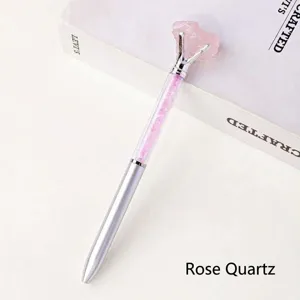 Close-up detail of natural raw rose quartz crystal metal ballpoint pen for office stationery.