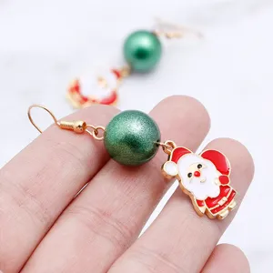 Close-up detail shot of Christmas Santa Claus drop earrings with green pearl and gold hook.