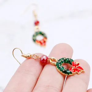 Close-up detail shot of exquisite Christmas wreath earrings featuring red crystal beads and gold hooks.
