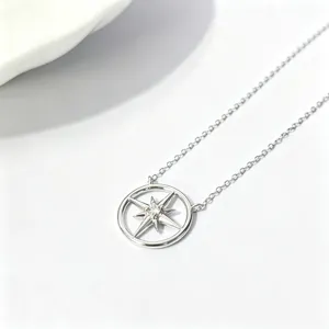 Closeup of sterling silver compass star pendant necklace, delicate hollow circular design detail.