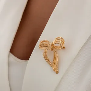 Detailed shot of an elegant gold multi-strand bow brooch pinned on a white blazer.