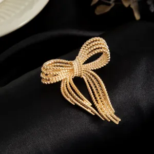 Close-up of elegant gold bow brooch featuring intricate multi-strand beaded design details.